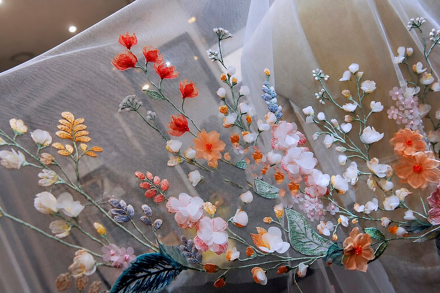 Close up of colorful floral embroidery and 3D appliqués on light ivory bridal veil