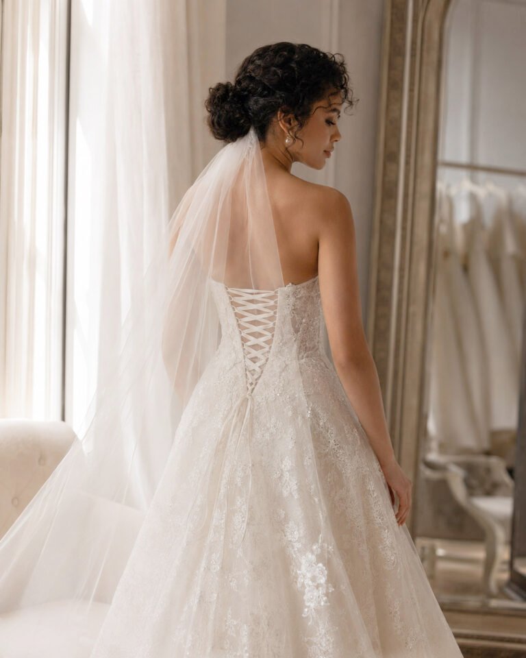 Bride wearing an ivory corset back wedding dress with lace-up closure and sheer veil