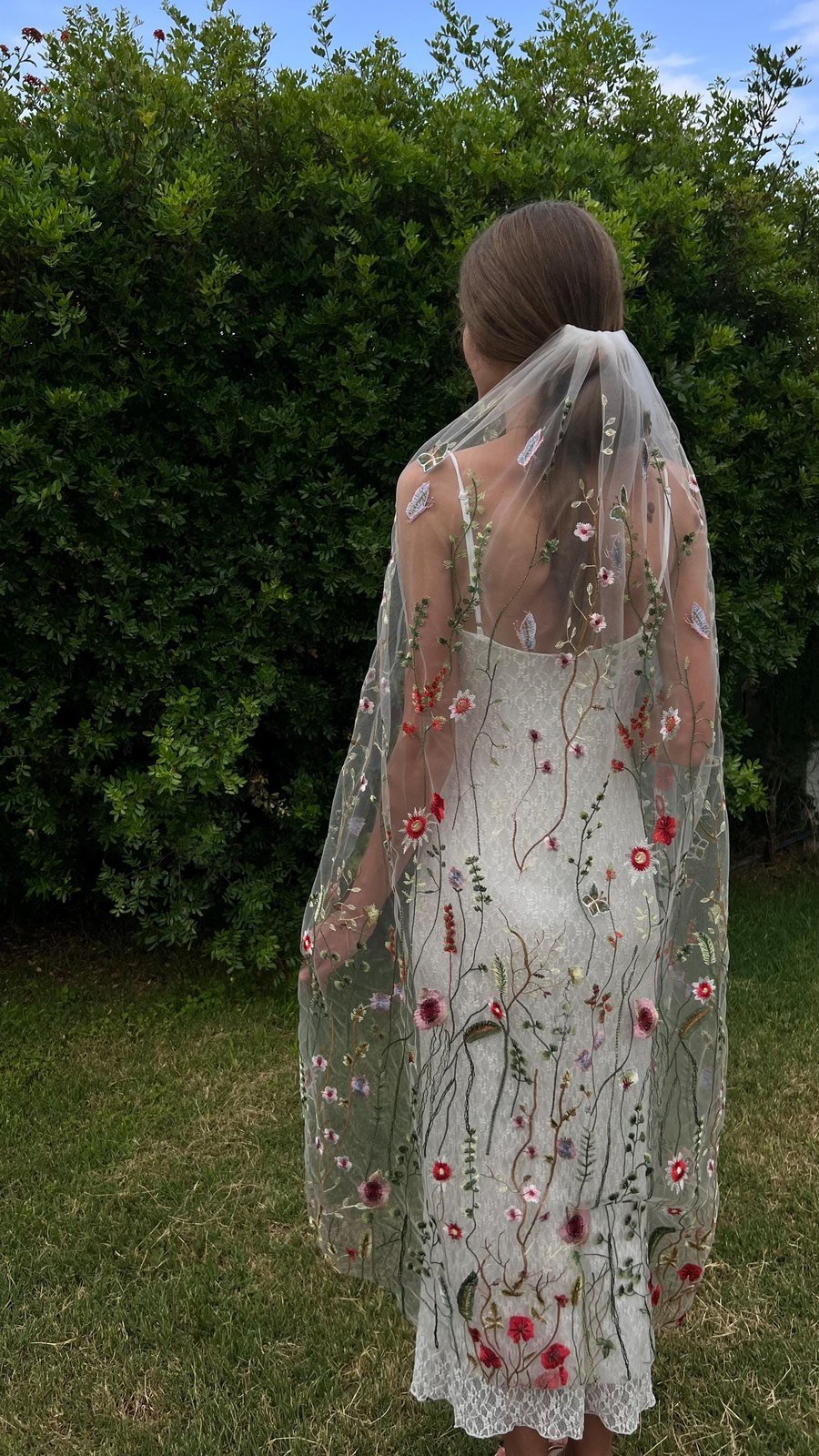 Full-length view of embroidered floral wedding veil worn outdoors