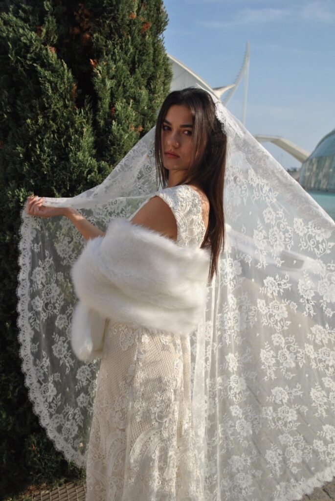 Bride wearing a light ivory embroidered lace mantilla wedding veil outdoors