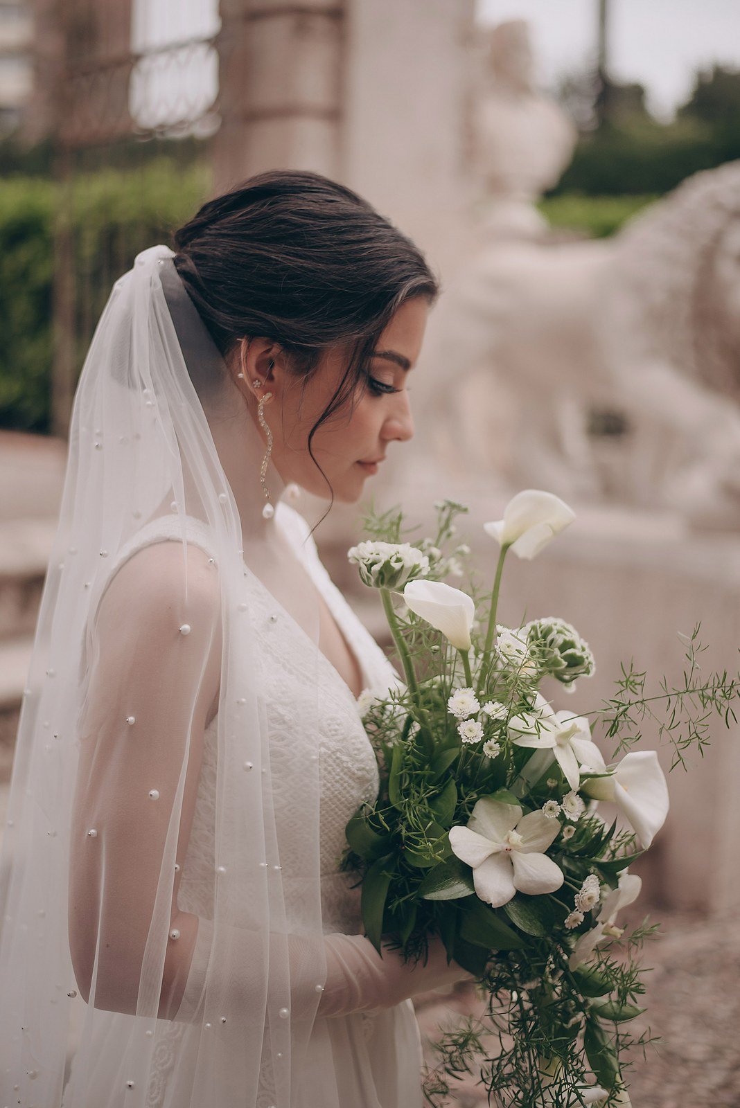 Bride wearing a two-layer pearl wedding veil while holding a white flower bouquet