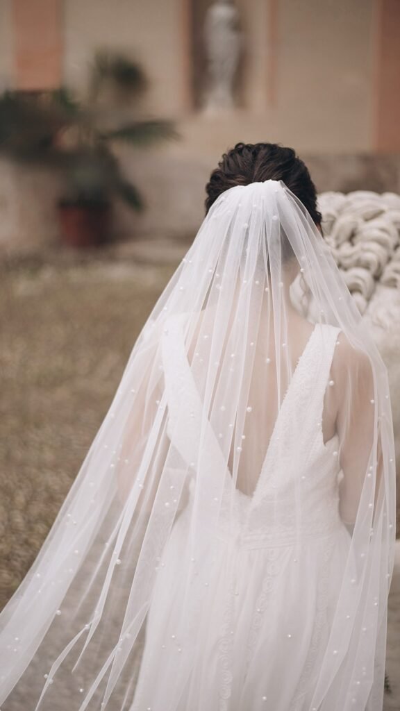 Back view of a bride wearing a long single-layer pearl wedding veil