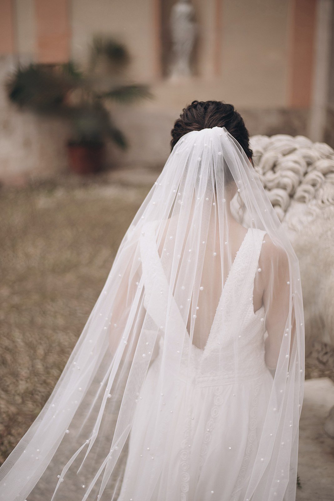 Back view of a bride wearing a long single-layer pearl wedding veil