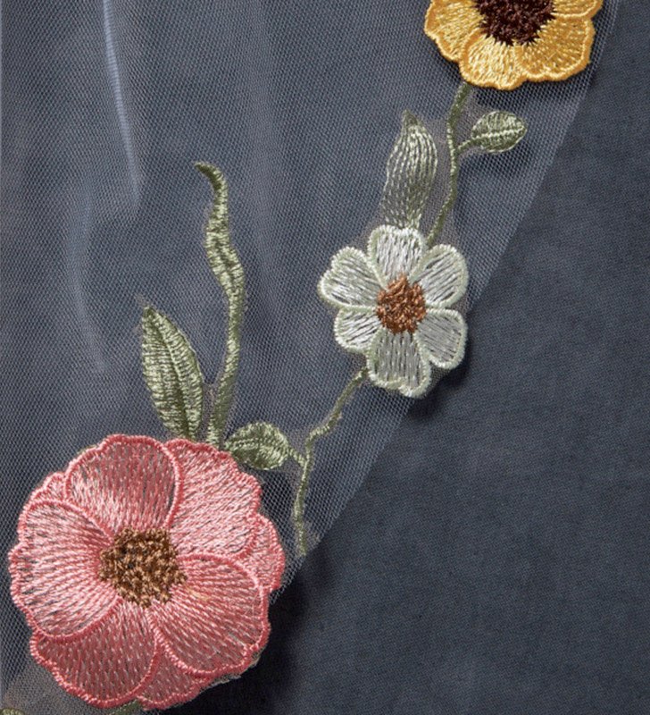 Close-up of pink yellow and white floral embroidery on transparent bridal tulle