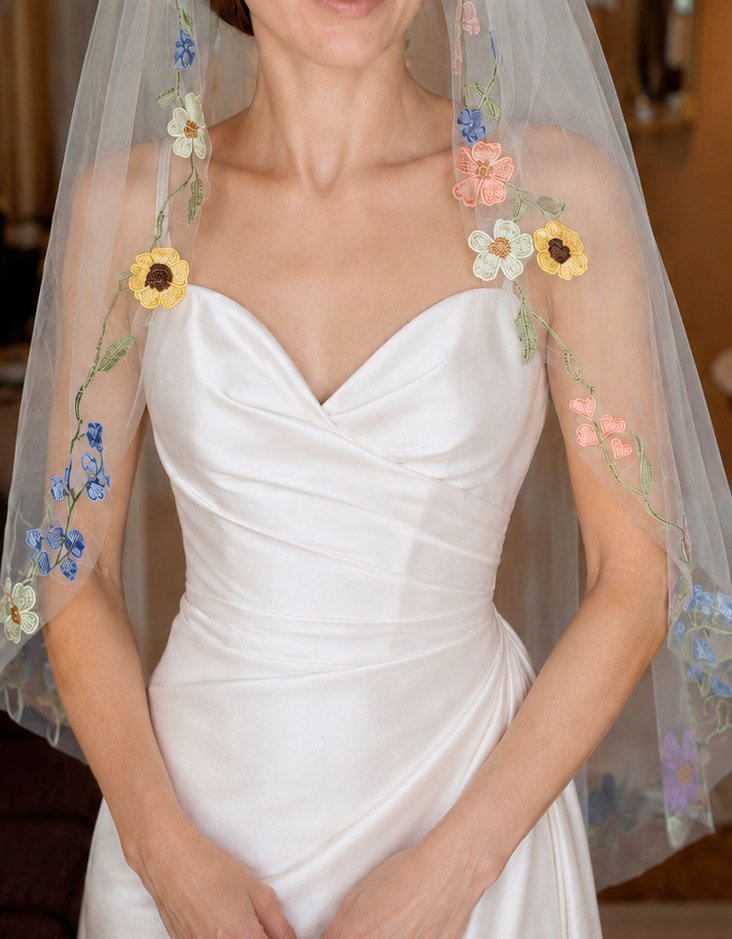 Close-up of bride wearing a short colorful floral bridal veil with embroidered flowers